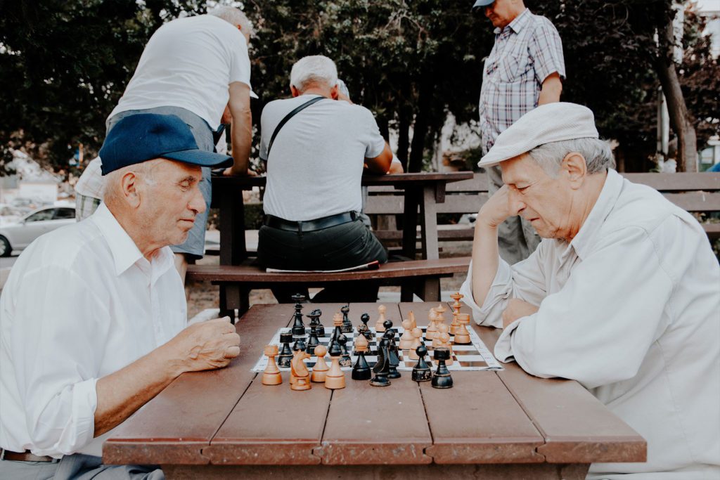older men playing chess outside